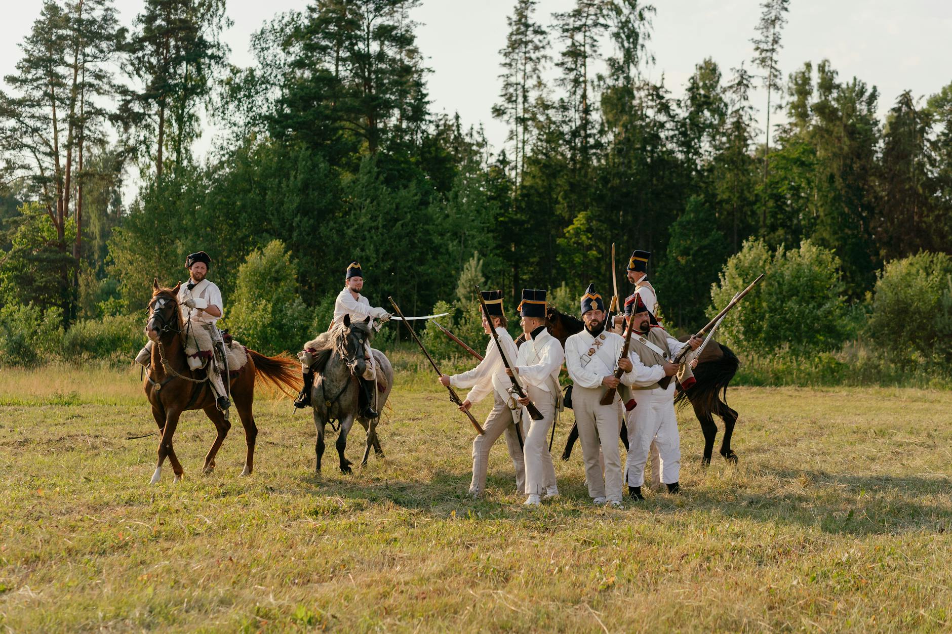 Rekonstruktorzy wojskowi pieszo i konno na zielonej łące