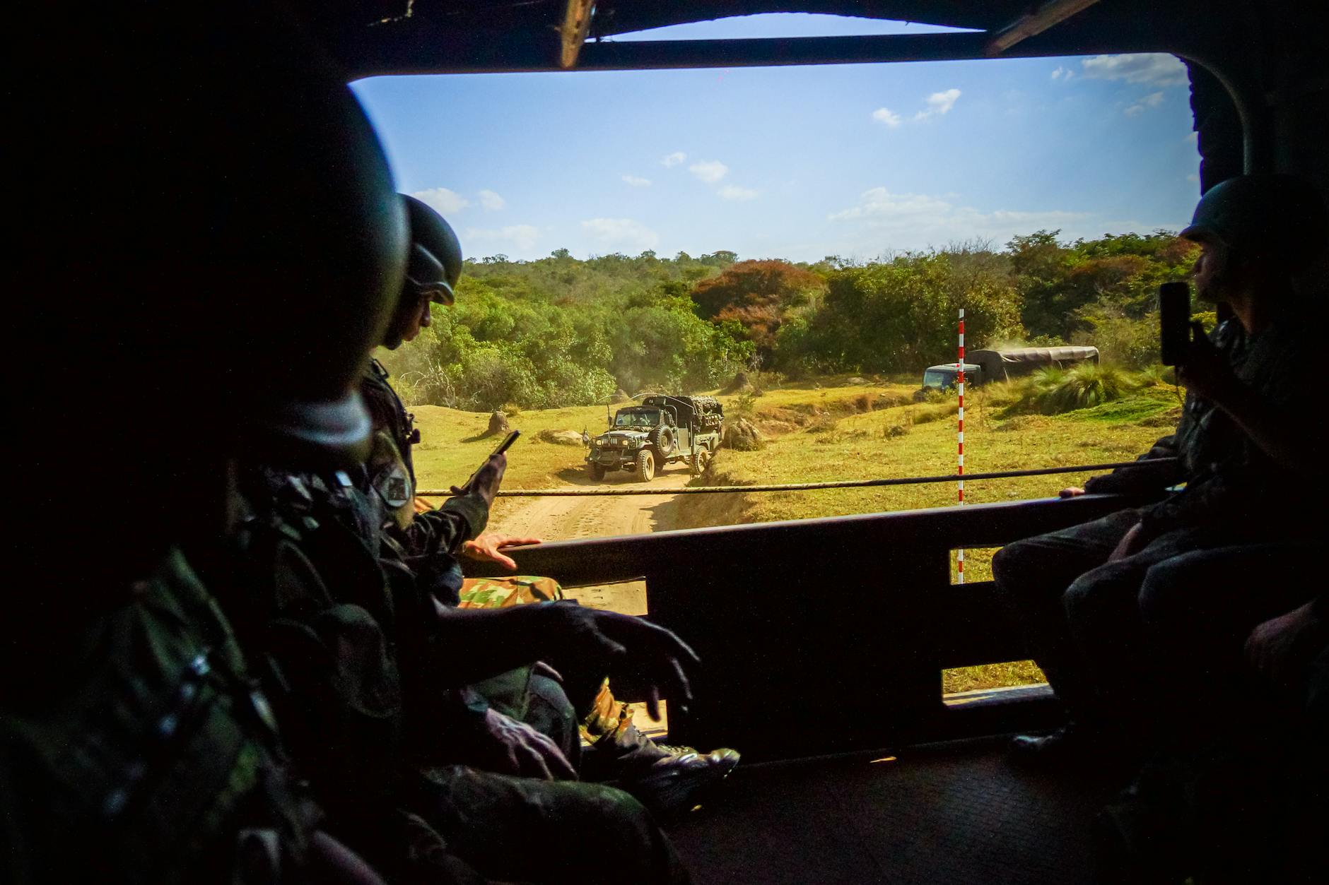 Żołnierze w transporterze opancerzonym obserwują ćwiczenia w słoneczny dzień