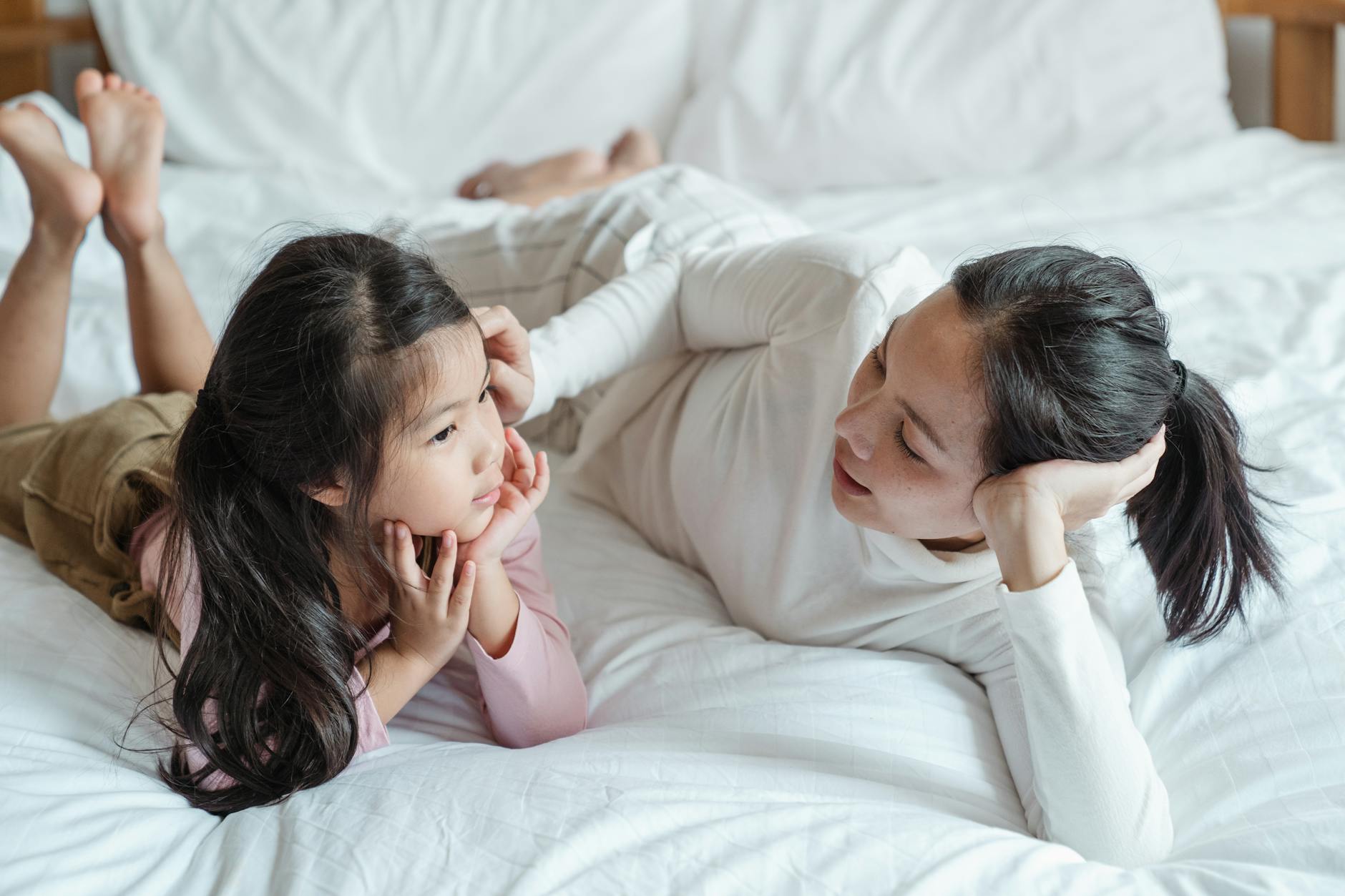 Mama i córka leżą na łóżku i rozmawiają w przytulnym pokoju